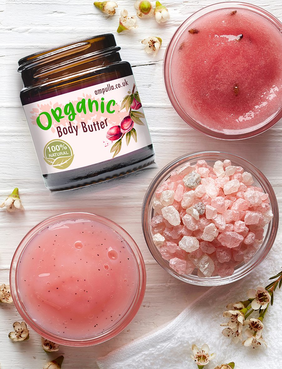 Cosmetic cream container, body scrub, bath salt and pink flowers on white wooden background from top view